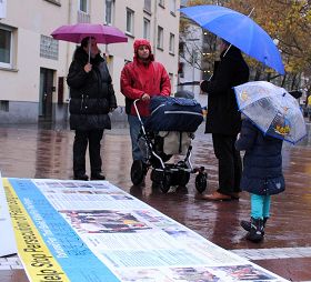 '民众在雨中听法轮功学员讲真相'