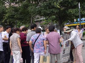 '许多游客围住一位法轮功学员听真相'